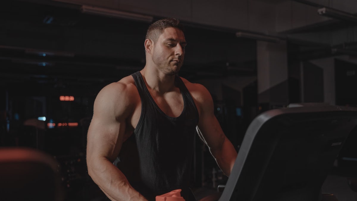 A bodybuilder working out on a treadmill at the gym, focused on fitness and strength training.